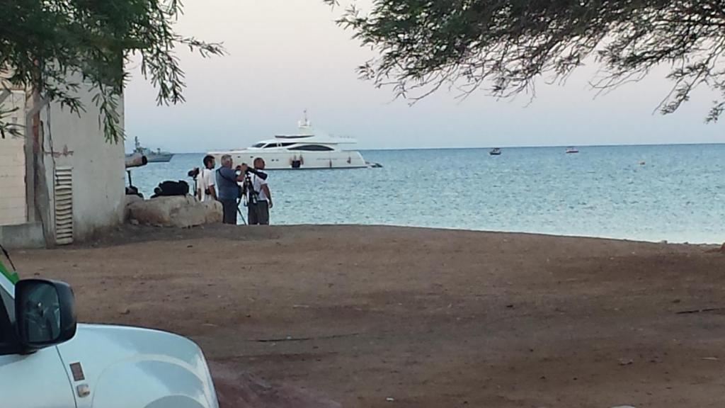 a group of people standing near the water with a boat at Caravan In the Desert in Eilat