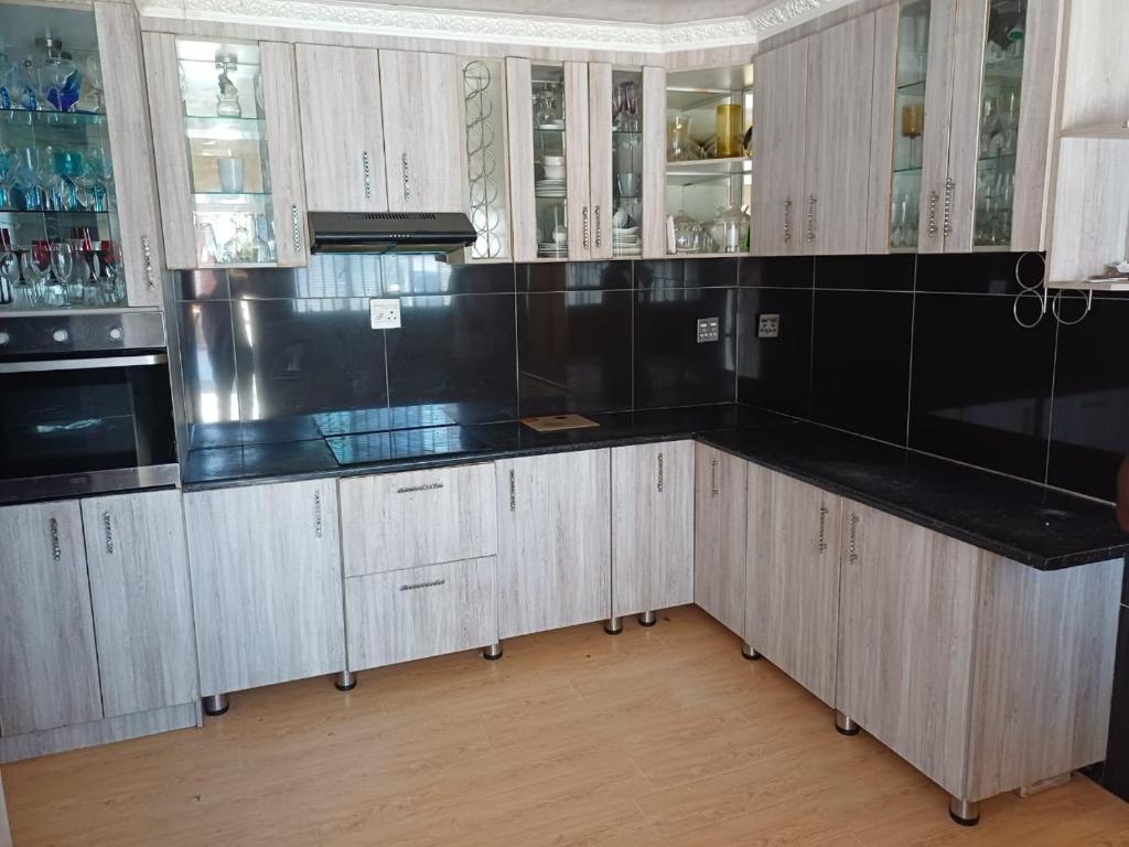 une cuisine avec des armoires blanches et des comptoirs noirs dans l'établissement Sweet Home Guest House, à East London