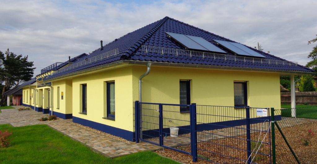 une maison jaune avec des panneaux solaires sur le toit dans l'établissement Ferienhaus Sonnenseite-Rechts, nur 100m vom Senftenberger See, à Senftenberg