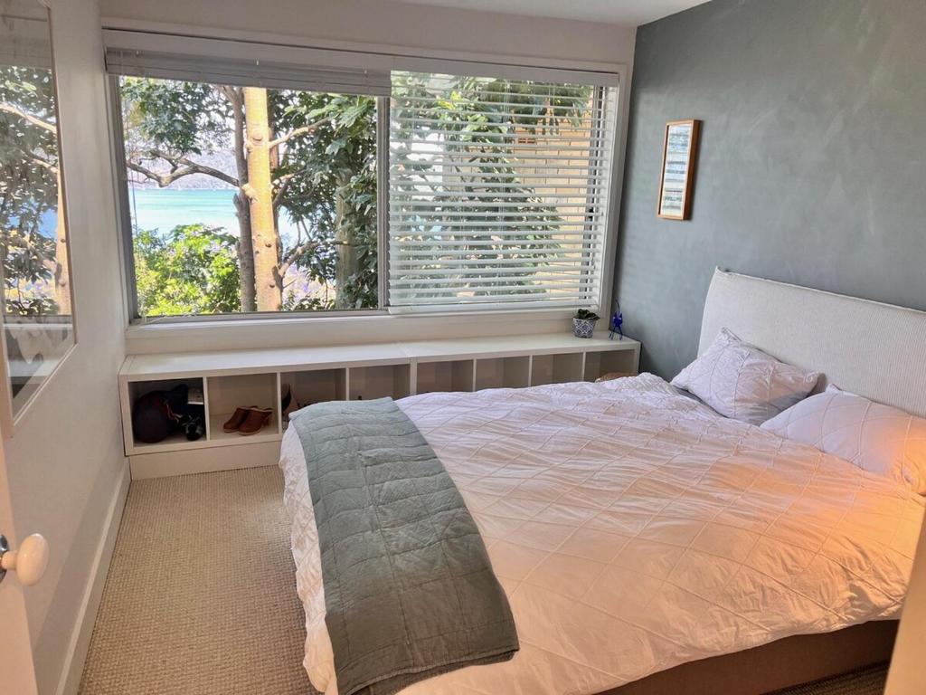 a bedroom with a large bed and two windows at Capri House in Clareville