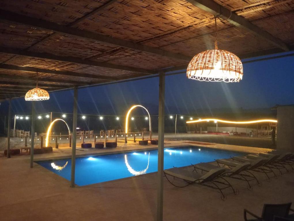 a swimming pool with two chandaliers and two lights at LA HACIENDA Agafay Desert 