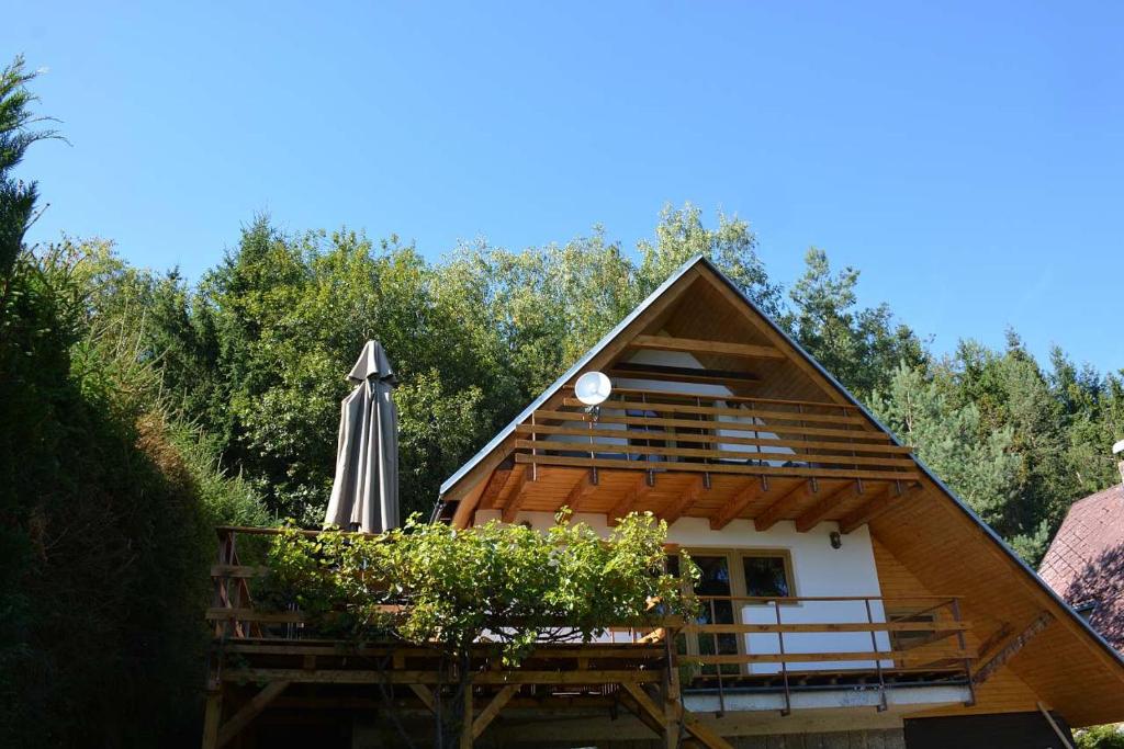a small house with an umbrella and a deck at Chata Šumavěnka in Bezděkov