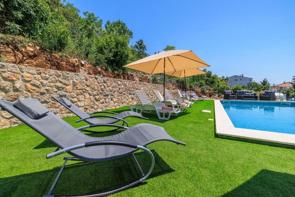 a group of chairs and an umbrella next to a pool at Apartments San in Dramalj