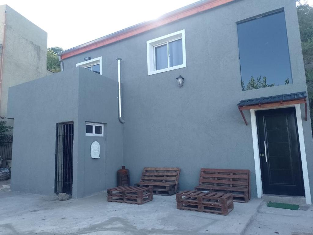 un edificio con tres bancos de madera junto a una puerta en Vivi el momento, en Río Ceballos