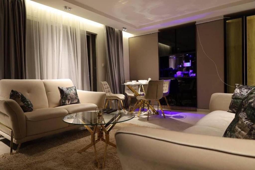 un salon avec des canapés blancs et une table dans l'établissement Appartement calme et luxueux, à Hydra