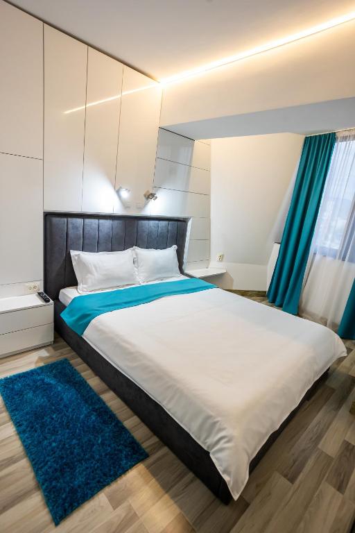 a bedroom with a large bed with blue rugs at Mara Park in Baia Mare