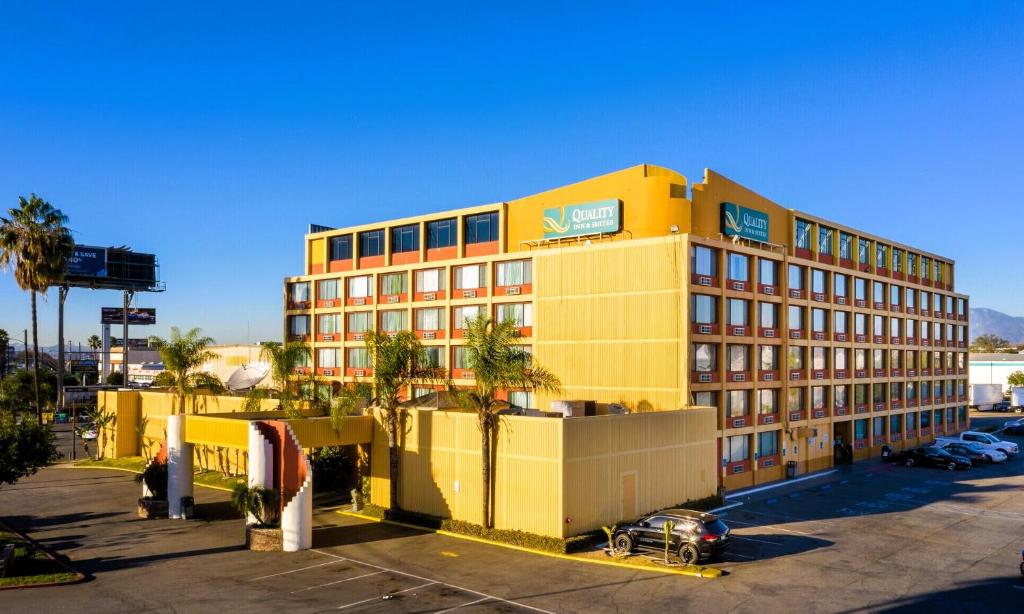 a yellow building with palm trees in a parking lot at Quality Inn & Suites Montebello - Los Angeles in Montebello
