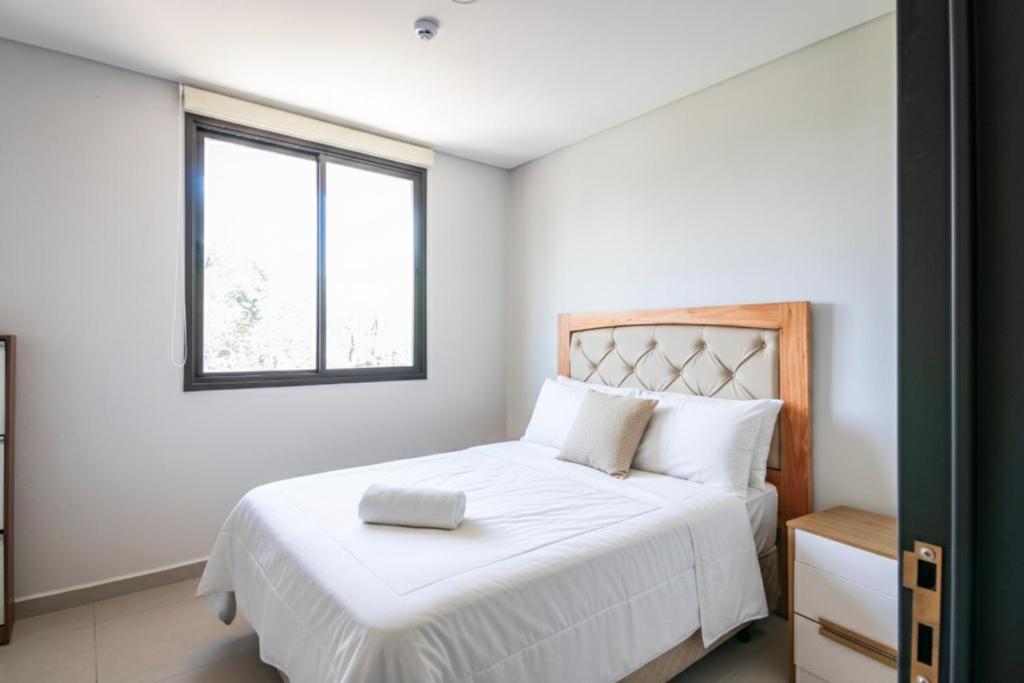 a bedroom with a white bed with a window at Calido 1BR Dpto, a minutos del Aeropuerto in Asuncion