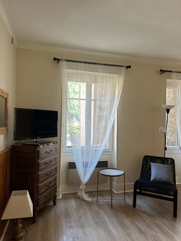 een woonkamer met een tv en een stoel en een raam bij Studio Le Clocher in Saint-Étienne-de-Tinée