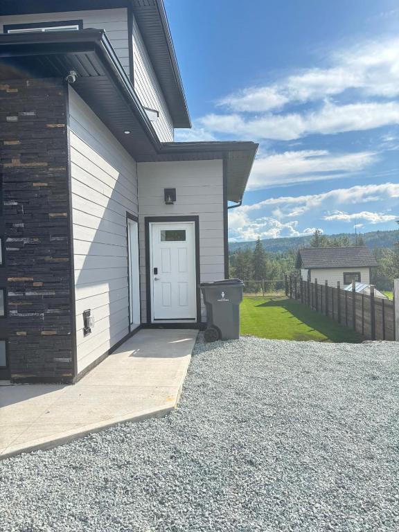 a house with a white door and a gravel driveway at Prince George Cozy Suite in Prince George