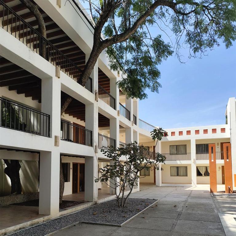 an apartment building with a tree in the courtyard at Hotel Azul Agave Oaxaca in Yelateni