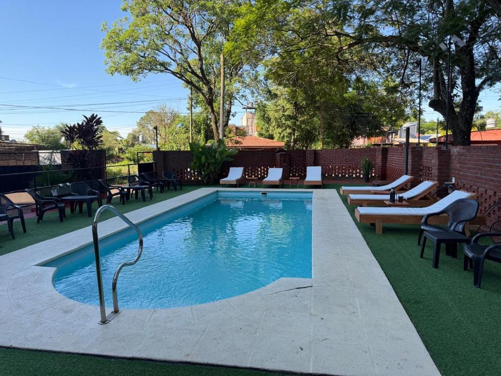 una piscina con algunas sillas y una mesa en Terra Iguazú Suites, en Puerto Iguazú