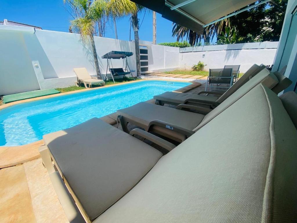 - une piscine avec des chaises longues à côté de la piscine dans l'établissement Villa H modern living steps from the beach, à Temara