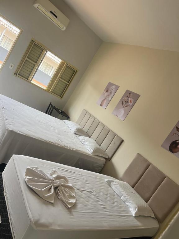 a bedroom with two beds and two pictures on the wall at Hotel Lupinetti in Jaciara