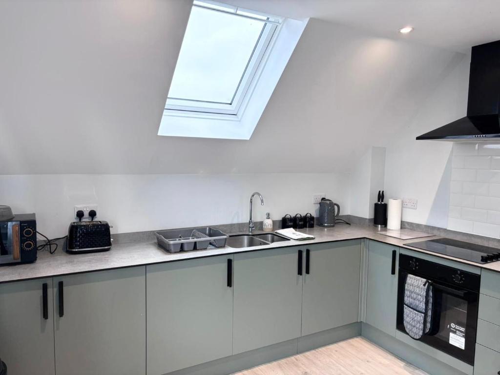 a white kitchen with a sink and a window at Modern Flat Near Dover Castle in Dover