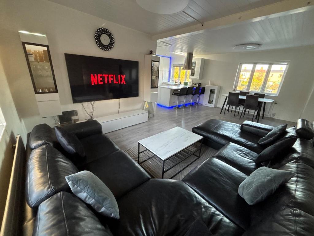 a living room with a black leather couch at Spacious & Cozy home with open kitchen lounge in Søborg