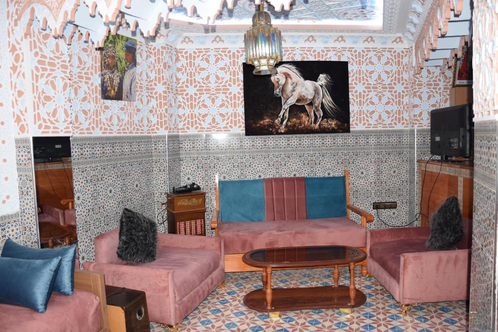ウジダにあるDiyafat Bladiのピンクの家具と馬の絵が飾られたリビングルーム
