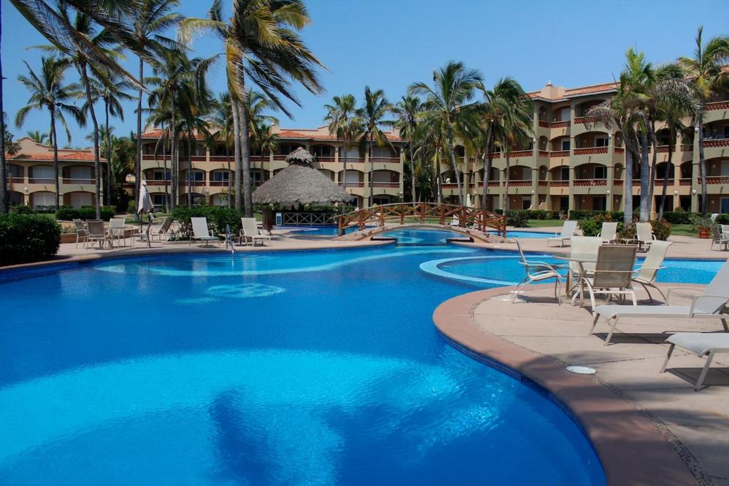 - une piscine avec des chaises longues et des palmiers dans l'établissement Ocean & golf resort condo in Mazatlán, à Mazatlán