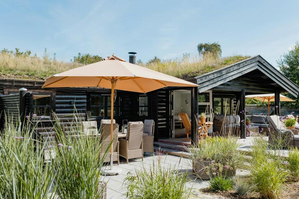 une terrasse avec un parasol devant un bâtiment dans l'établissement Hear The Sea From Log Cabin In Gilleleje, à Gilleleje