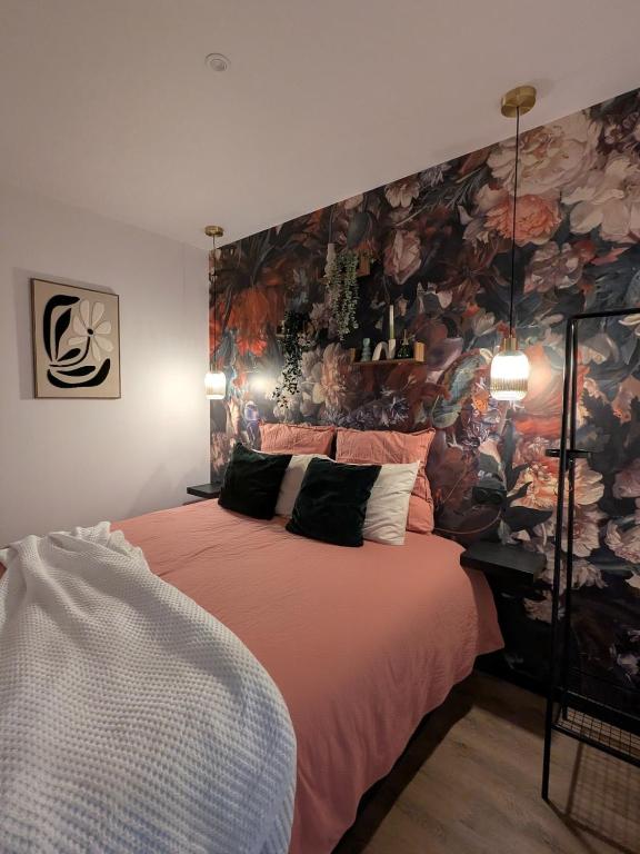 a bedroom with a large bed with a floral wall at Studio cosy proche étang et commerces in Saint-Aubin-du-Cormier