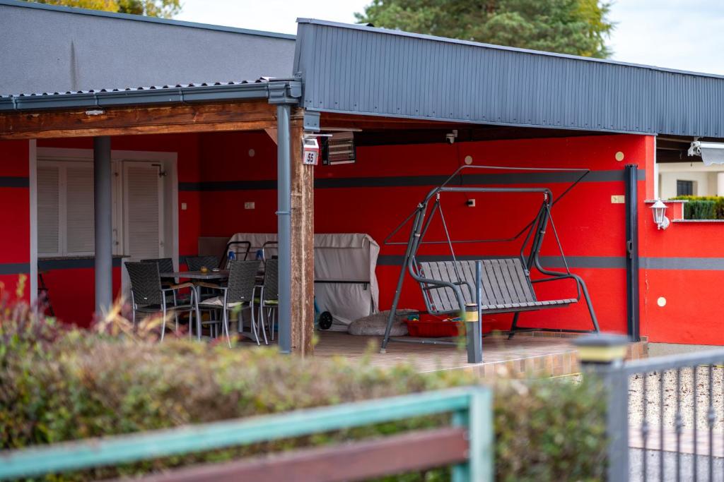 Un edificio rojo con un patio con sillas y un columpio. en Kuća za odmor NADA, en Legrad