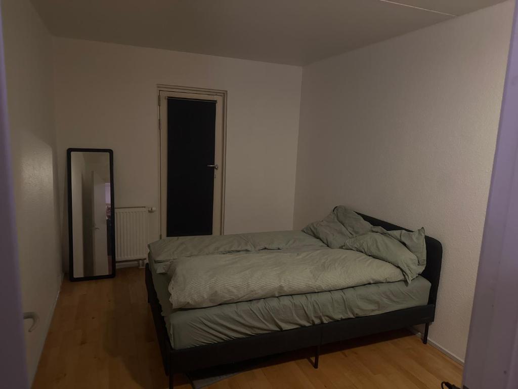 a bedroom with a bed and a mirror in it at Lejlighed in Måløv