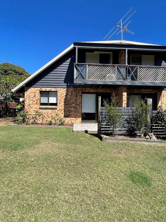 a brick house with a large lawn in front of it at The Loft in South West Rocks