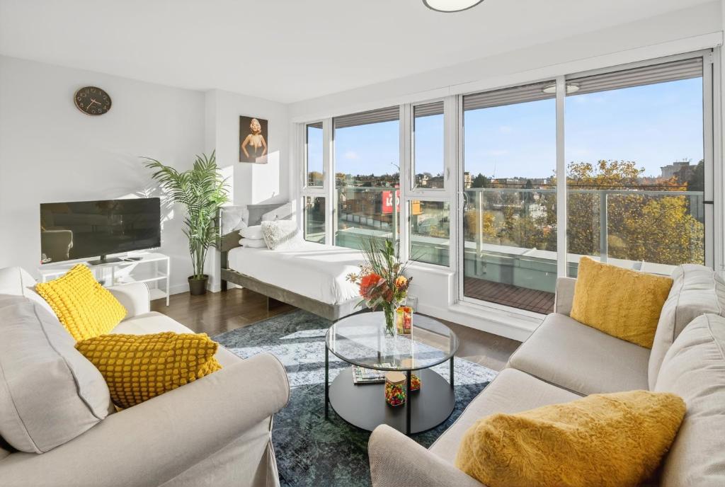 a living room with white furniture and a large window at Stylish 2 Bed Condo Near Transit and Amenities in East Hastings in Vancouver