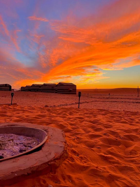 Una puesta de sol en la playa con un edificio en la arena en Wadirum sunset camp, en Wadi Rum