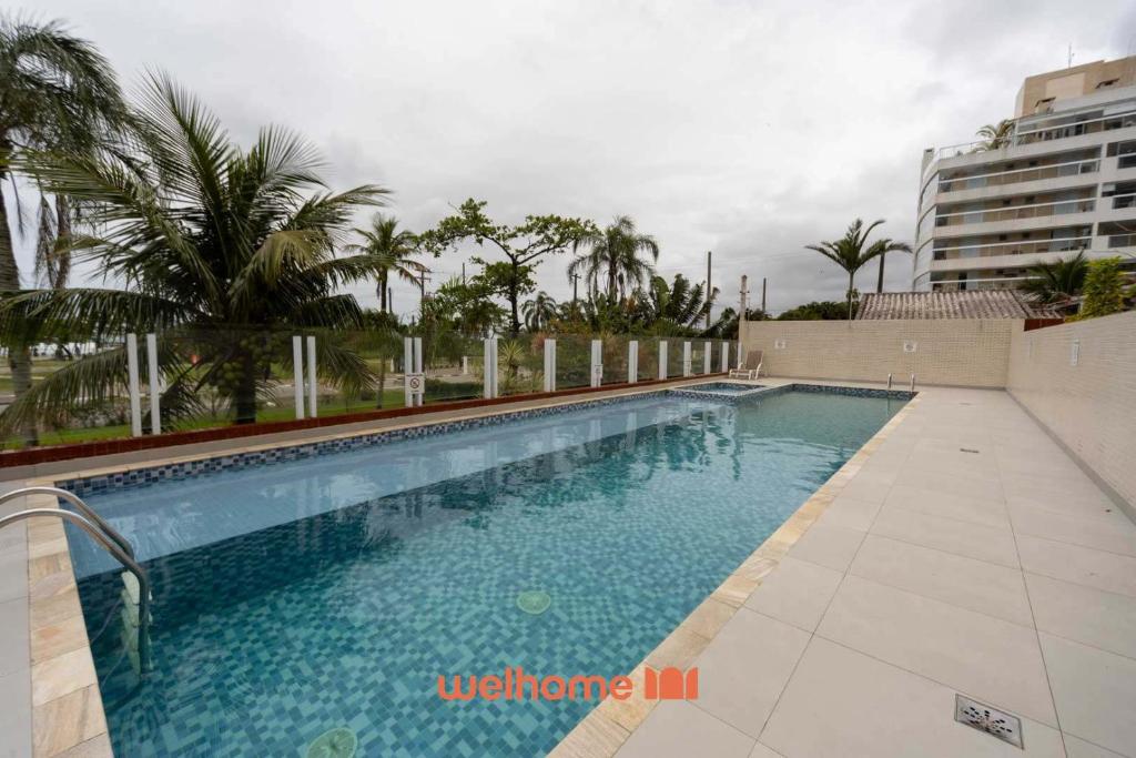 a large swimming pool with palm trees and a building at Apartamento em Bertioga a 500m da Praia de Indaiá in Ilha Monte Pascoal
