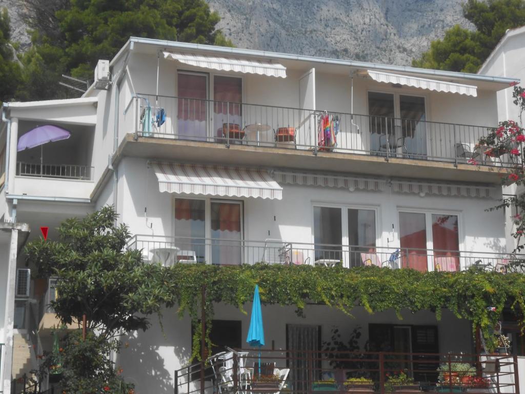 Casa blanca con balcón con sombrilla azul en Apartments Nina M en Baška Voda