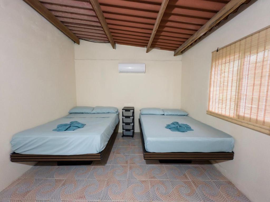 two twin beds in a room with a window at Nilka sunset house in Colón
