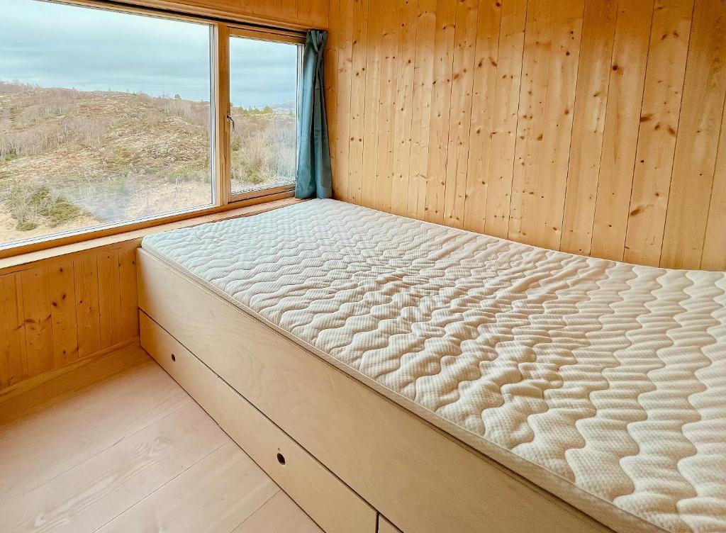 a bed in a wooden room with a window at Architect Drawn Cabin With Sea View At Stokkøy in Hosen