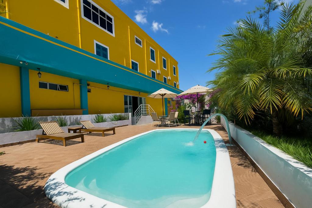 a swimming pool in front of a yellow building at Pousada Serra Bella in Tianguá