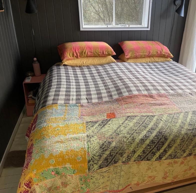 1 cama con edredón y 2 almohadas en Little Oneroa Beach Bach, en Waiheke Island