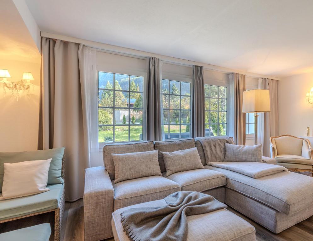 een woonkamer met een bank en een aantal ramen bij Mountain Residence in Kandersteg