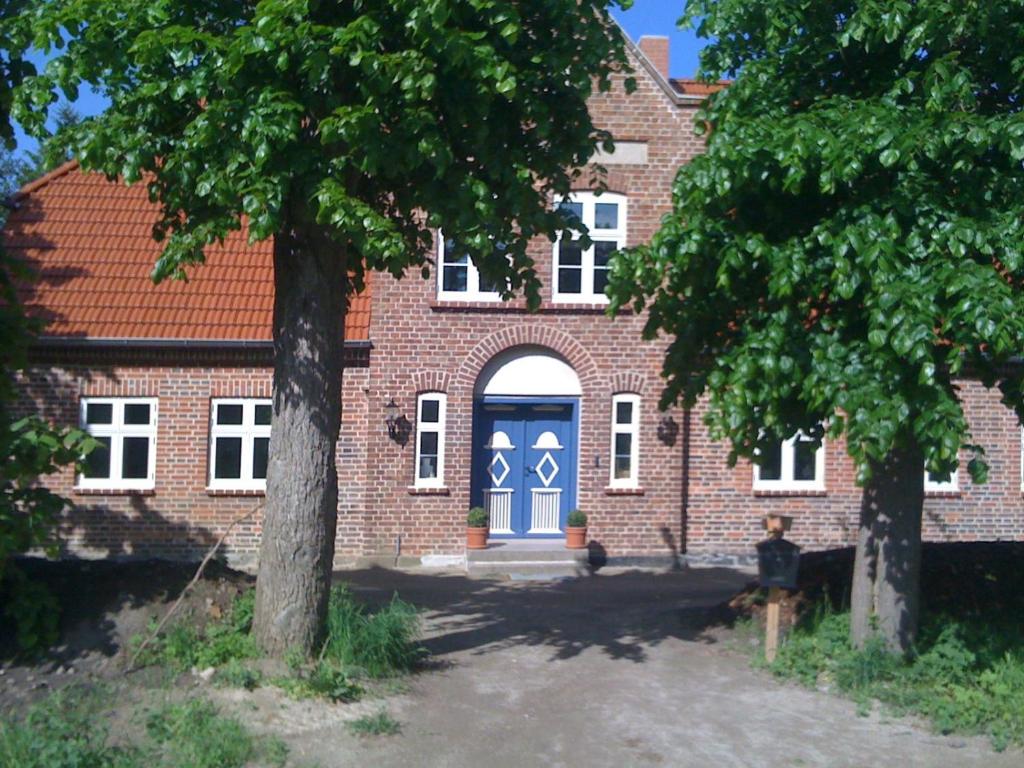 a brick building with a blue door and two trees at Gutshaus Vieregge in Neuenkirchen