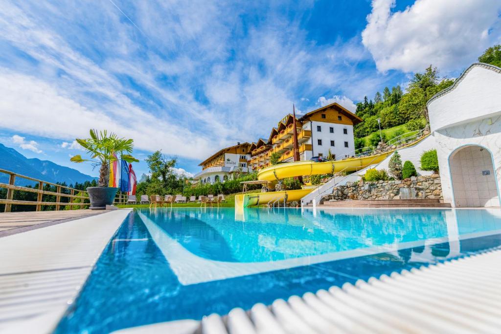 a swimming pool with a resort in the background at Hotel Glocknerhof in Berg im Drautal