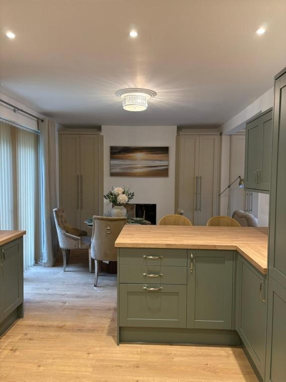 a kitchen with green cabinets and a dining room at Luxury Four Bedroom House in Rock Ferry