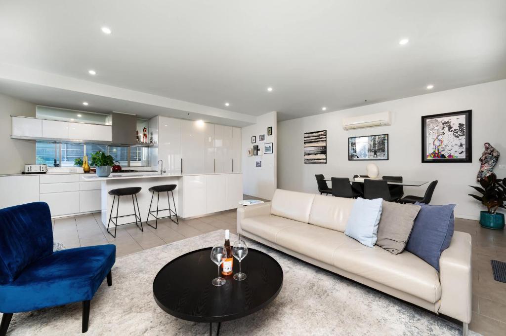 un soggiorno con un divano bianco e un tavolo di Fitzroy 2BR Patio Parking & Pet-Friendly a Melbourne