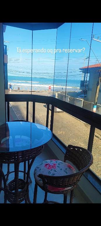 a table and chairs on a balcony with a view of the beach at AP BEIRA MAR 6 MINUTOs DO BETO CARRERO in Navegantes