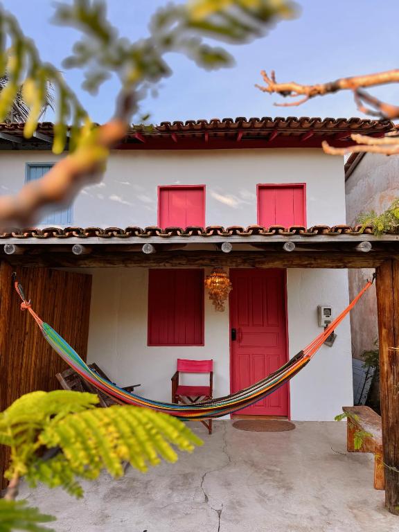 a hammock in front of a house with red doors at Casa Vulva Caraíva l Hostel feminino com vibe de lar in Caraíva