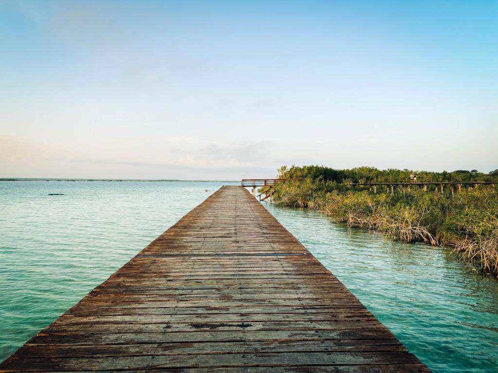 a wooden pier stretches out into the water at Viajero Bacalar Hostel in Bacalar