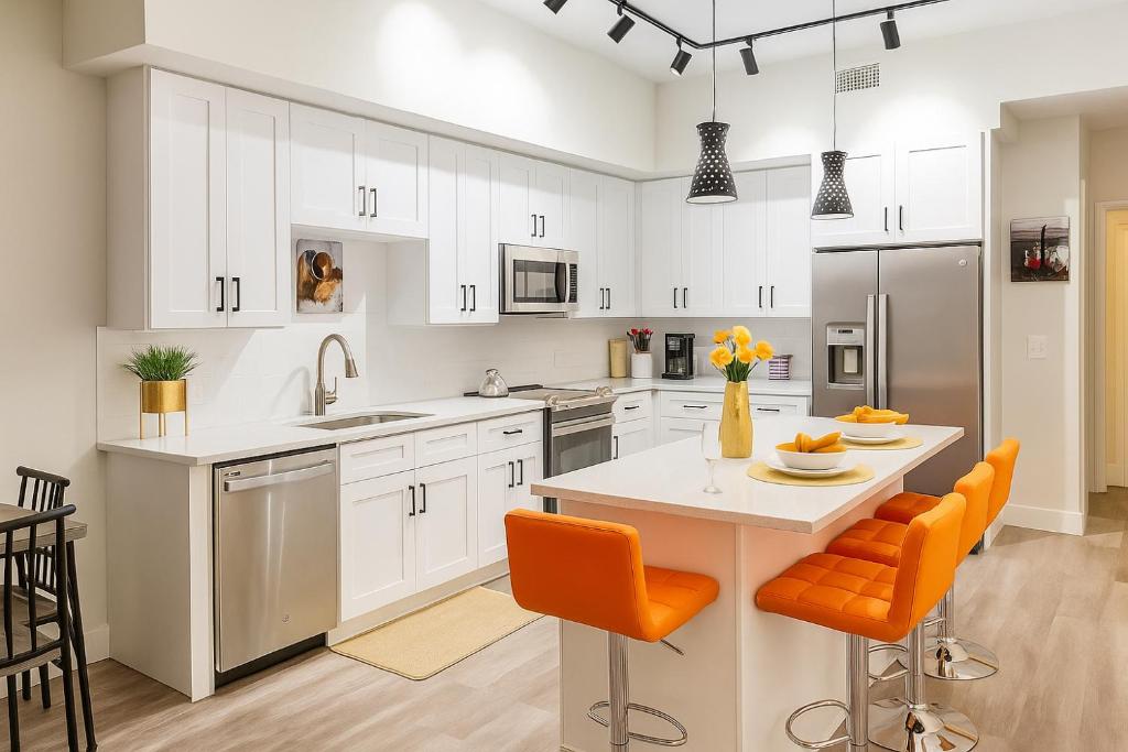 a kitchen with white cabinets and an island with orange chairs at Luxe & cozy 3Beds,2rooms,EV Gym Near Beaches&Downtown WPB in West Palm Beach