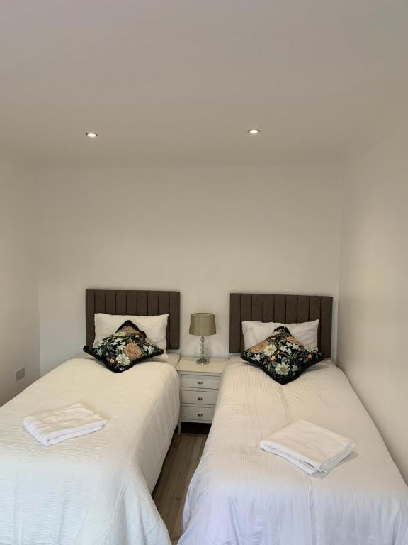 two twin beds in a room with white walls at Cosy Home Cardiff in Cardiff