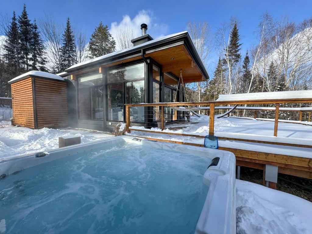 a hot tub in front of a house in the snow at Slow Living Lodge- SPA - Pet friendly in Saint Come