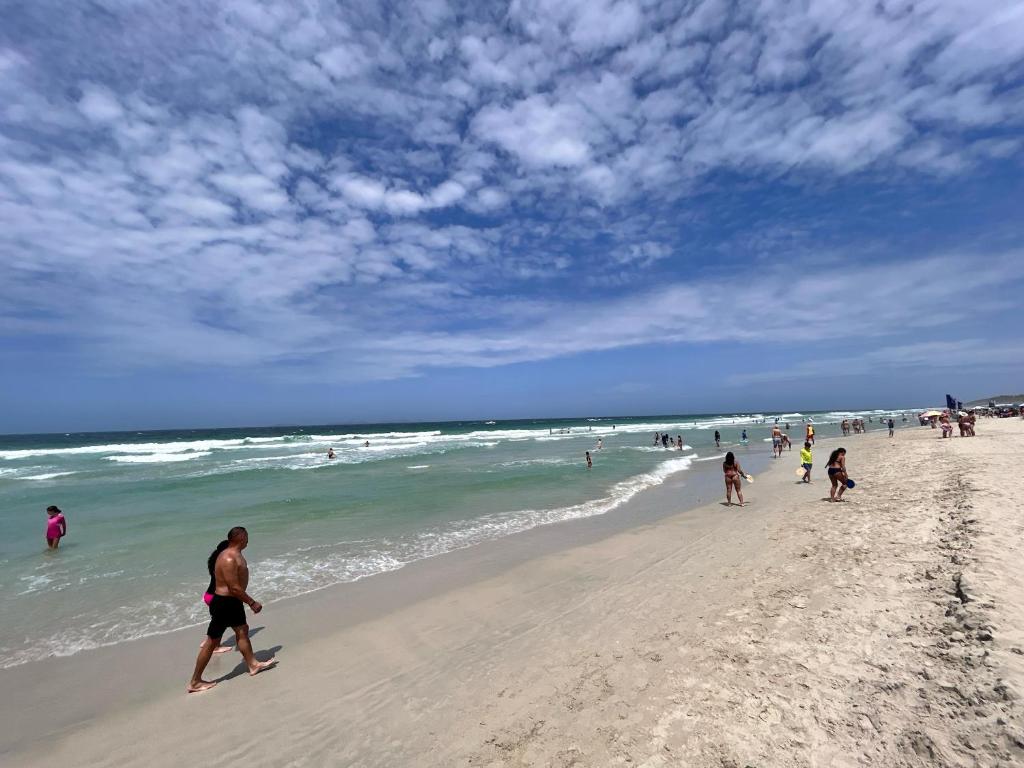 eine Gruppe von Menschen, die am Strand spazieren gehen in der Unterkunft Vida Playa el Agua in La Mira