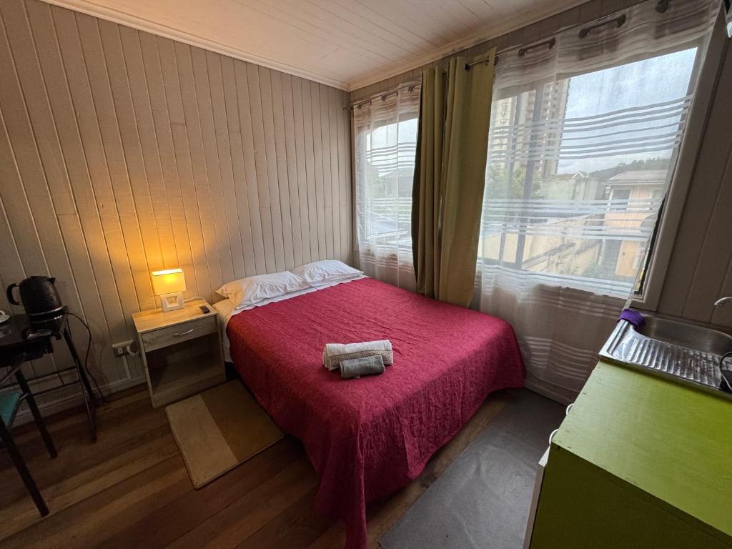 a small bedroom with a bed with a pink blanket at Hostal Raizén in Temuco