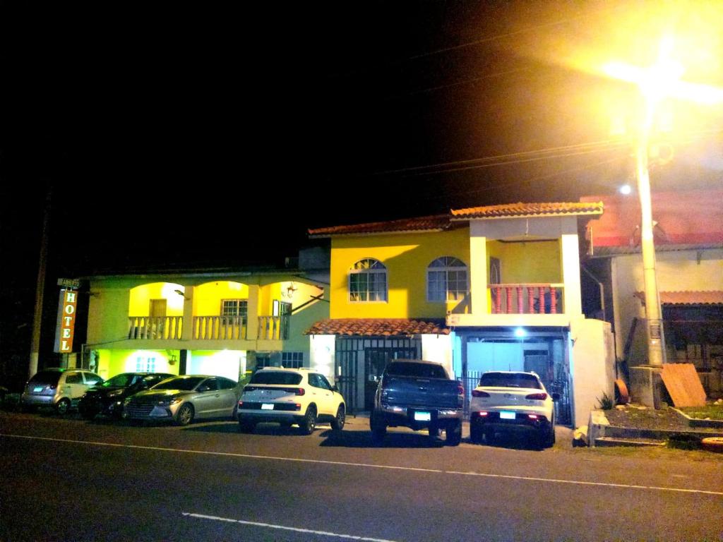 Un grupo de coches aparcados delante de una casa por la noche. en Hotel Gues, en La Guaca