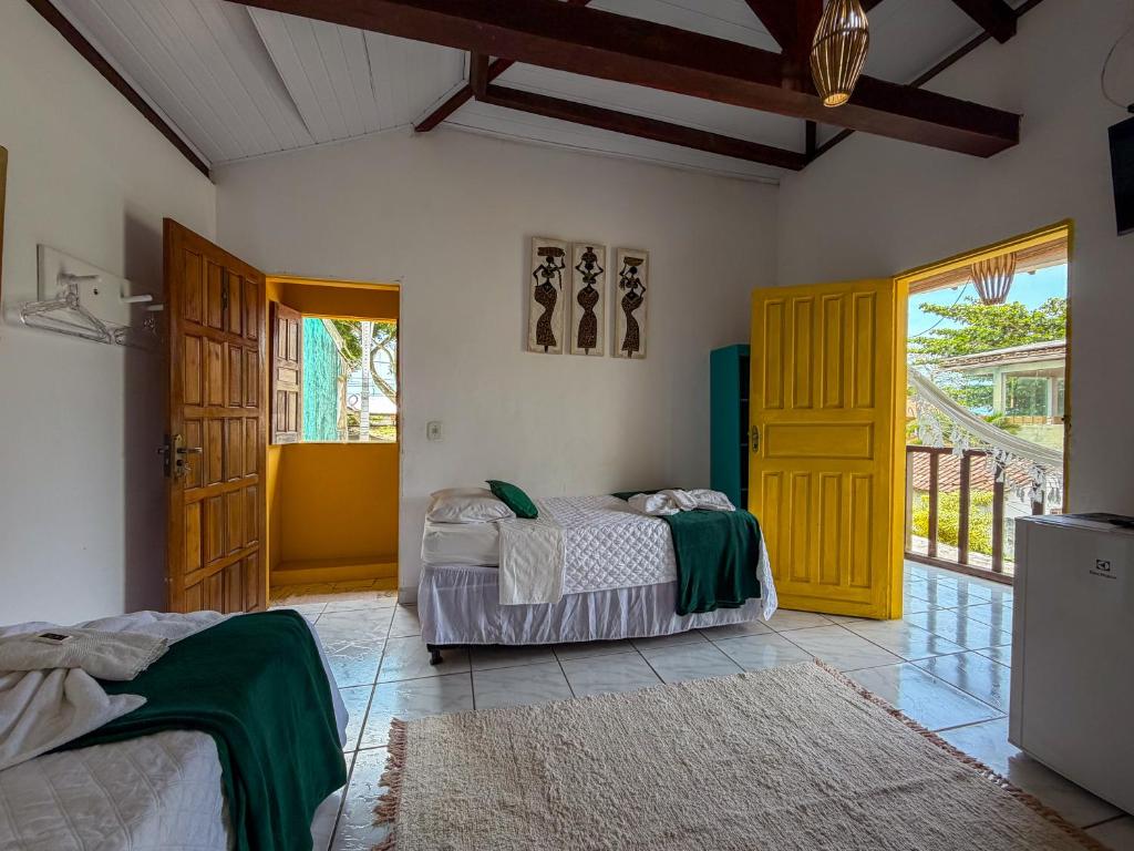 a bedroom with two beds and a yellow door at Pousada João Maria in Trancoso